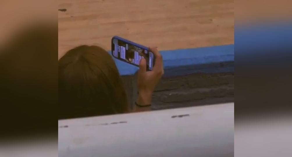 Una joven en El Salvador se hizo viral al ser grabada revisando el celular de su pareja mientras fingía grabar un partido de básquetbol. ¡El video que todos comentan! Foto: Cortesía.