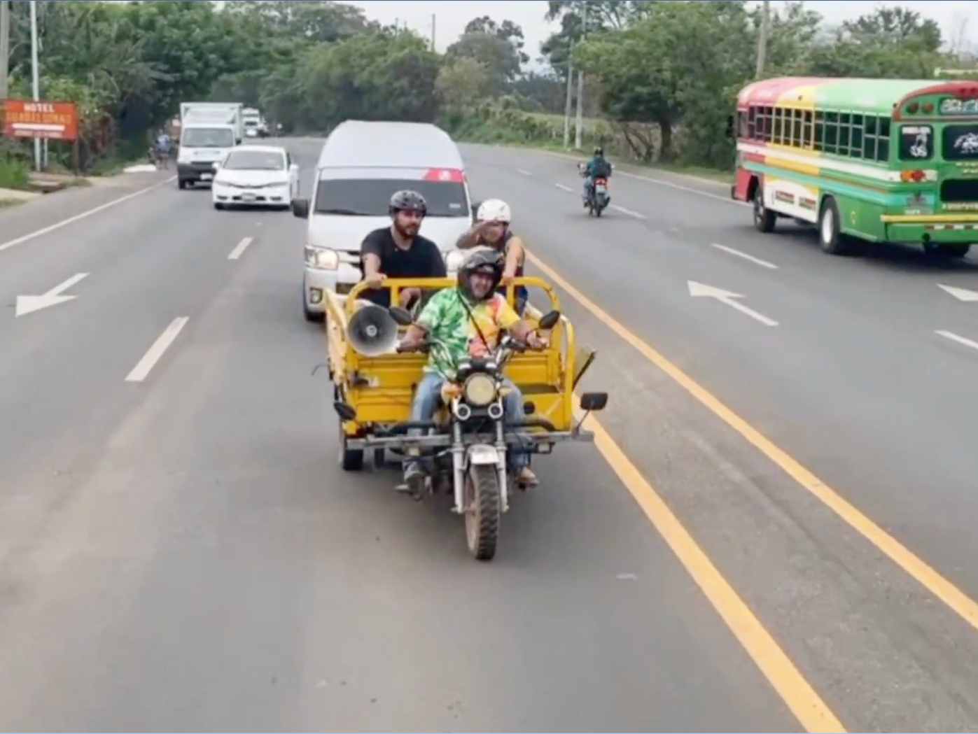 Los creadores de contenido cruzando la doble línea amarilla continua en carretera a bordo de una tricimoto de carga sin protección reglamentaria. Captura de pantalla